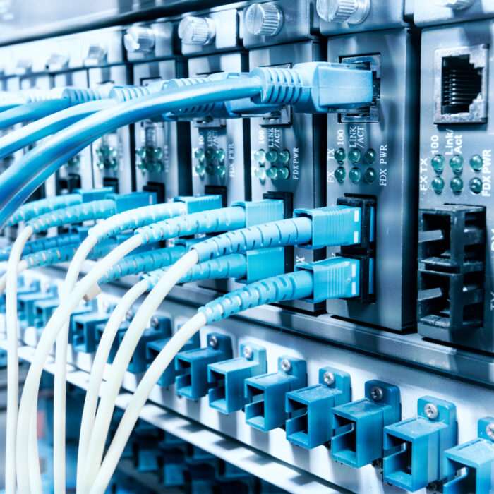 Close-up of network switches with multiple blue and white Ethernet cables connected, highlighting advanced telecom infrastructure in a high-tech data center or server room setup.