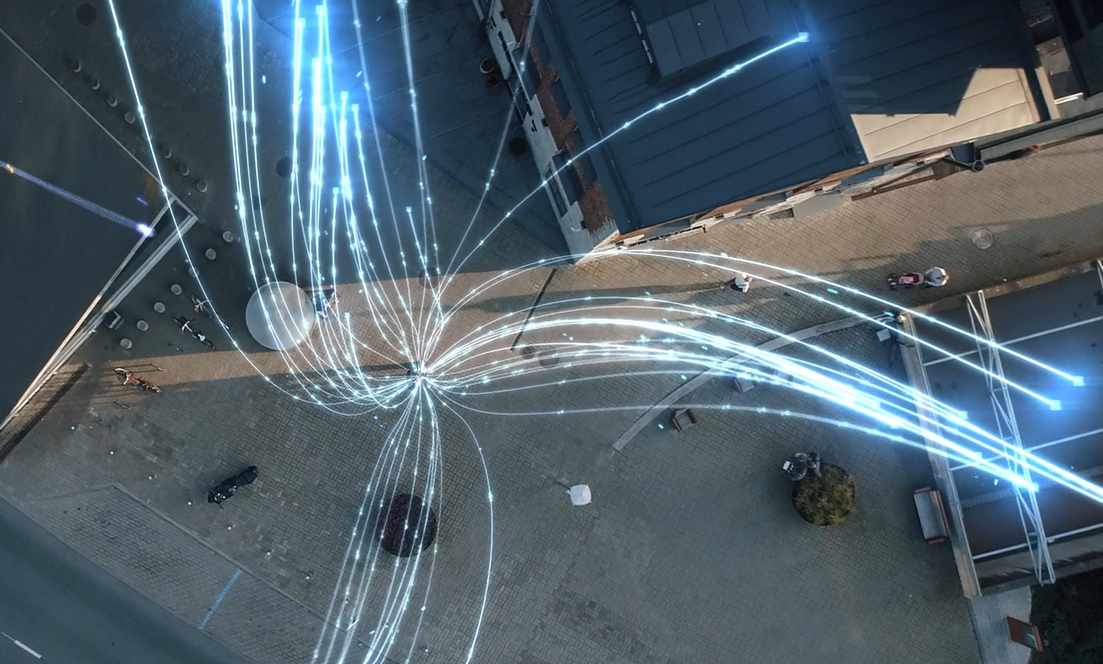 Aerial view of city streets with digitally added blue light trails converging at a central point, representing data flow or high-speed internet connectivity in an urban environment for the EVE Demonstration at Nottingham Trent University.