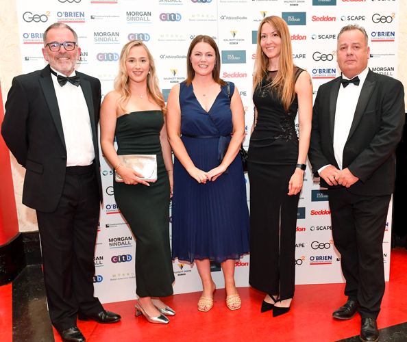 Five people dressed in formal attire stand on a red carpet in front of a sponsor backdrop, smiling at the camera at the Constructing Excellence East Midlands Awards, where Waldeck was celebrated as SME of the Year.