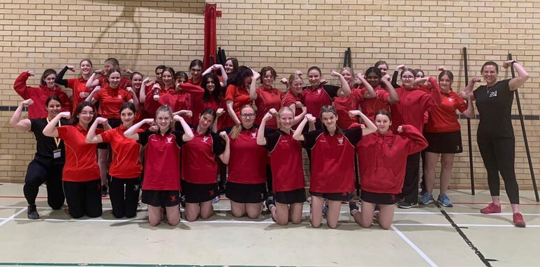 Two group photos of women and girls in red sportswear, likely from the Strong Girl Squad Academy, flexing their arms and smiling energetically in a gym at Lincoln UTC, united in front of a brick wall.